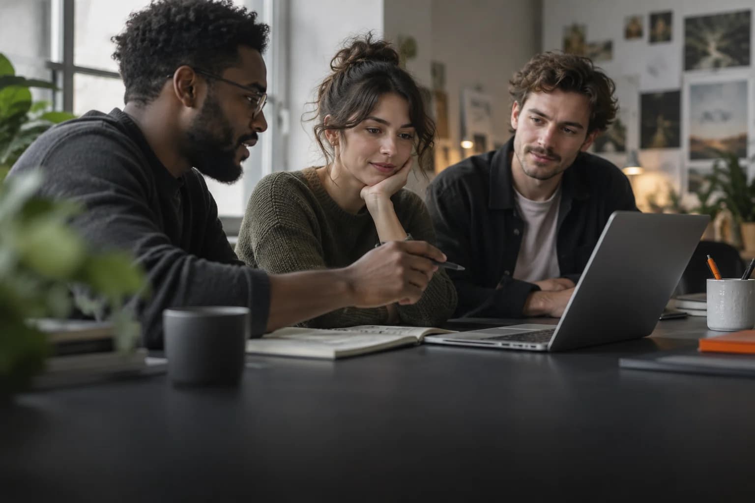 Three specialists reviewing work together around one laptop.